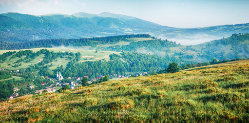 Fototapeta na wymiar Foggy morning panorama of mountains valley. Picturesque summer sunrise in Carpathian mountains, Rika village, Transcarpathian, Ukraine, Europe. Beauty of nature concept background.