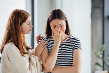 Obraz na płótnie Canvas teen girl supporting sad crying friend in striped t-shirt