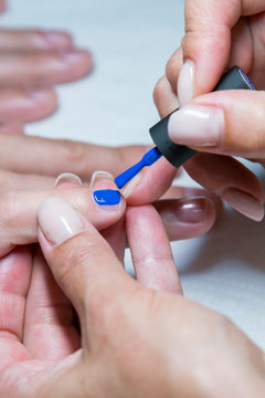 Beautiful manicure process. Nail polish being applied to hand, polish is a blue color. close up. vertical photo