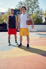 Full-length picture of two athletes with basketball on playground .