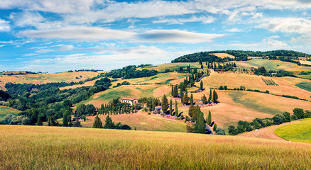 Obraz premium Classic Tuscan view with farmhouse and cypress trees. Colorful summer view of Italian countryside, Val d'Orcia valley, San Quirico d'Orcia location. Beauty of countryside concept background.