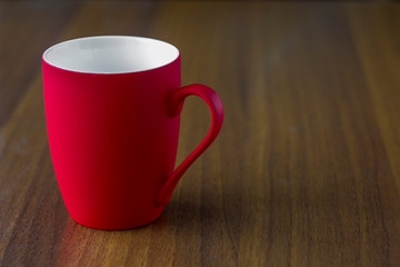 empty bright red porcelain mug close-up on a wooden table