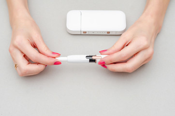 Woman's hands holds an electronic cigarette. Insert a cigarette into the mouthpiece. Smoking, health, struggle, addiction