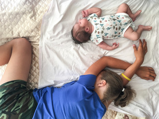 Two sisters a newborn baby and teenage girl sleeping on bed together, top view