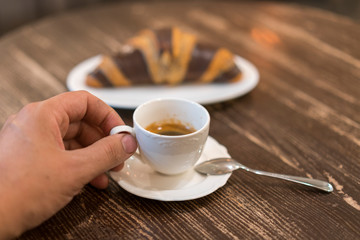 Fresh and tasty croissants with chocolate and cup of coffee on wooden background