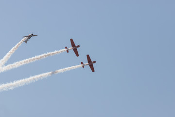 Three colorful jets flying in the blue sky and performing a show leaving smoke marks