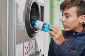 Child recycling plastic bottles in a machine