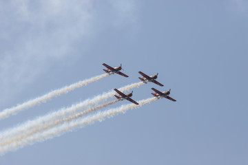 Four military jets flying in the blue sky and performing a show leaving smoke marks