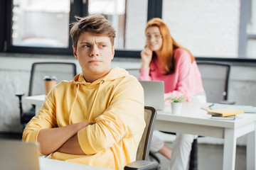 pensive schoolchildren sitting at desks with laptops in school