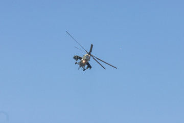 Fototapeta na wymiar A green military helicopter flying towards the camera - clear blue sky