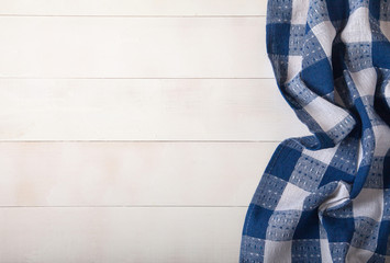 A linen napkin with blue cells lies on a white wooden background. Flat lay. Copy cpaes.