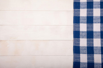 Fototapeta na wymiar A linen tablecloth with blue cells lies flat on a white wooden background. Horizontal