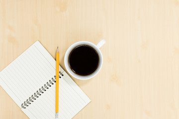 Top view of notebook pencil and cup of coffee on wood table background.Business desk minimal style concept with copy space for any design.Flat lay.