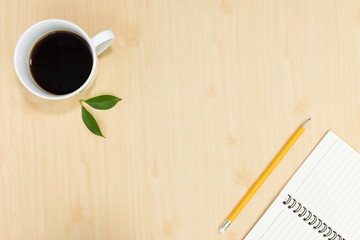 Top view of notebook pencil and cup of coffee on wood table background.Business desk minimal style concept with copy space for any design.Flat lay.