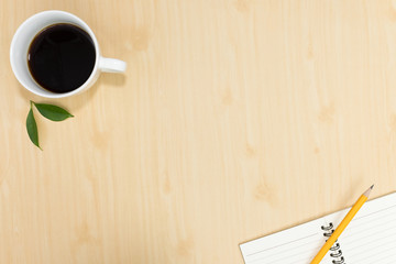 Top view of notebook pencil and cup of coffee on wood table background.Business desk minimal style concept with copy space for any design.Flat lay.