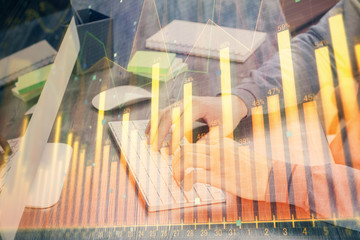 Stock graph with businessman typing on computer in office on background. Concept of analysis. Double exposure.