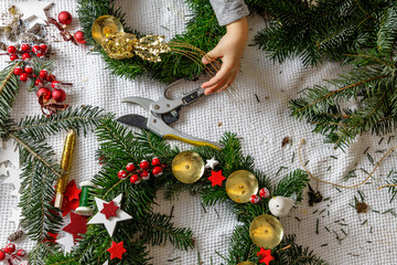 Hands of a child decorate Christmas Advent wreath from fir twigs