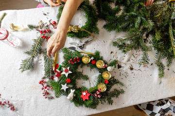 Hands of a woman make Christmas Advent wreath from fir twigs