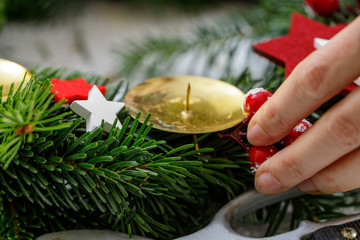 Hands of a woman decorate Christmas Advent wreath from fir twigs