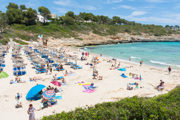 People relax on the beach in Cala Mandia Bay