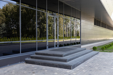 Glass doors reflecting green bushes and trees in the opposite side and stone steps