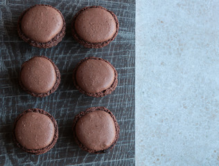 six chocolate macarons on wooden background
