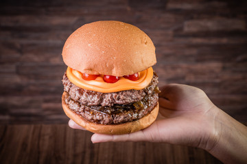 Double craft beef burger with cheddar cheese, caramelized onion.and pepper pout on wood table and rustic background.