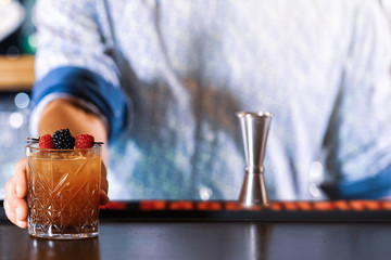 Bartender making delicious cocktails in the bar. (high ISO and shallow dept of focus image)