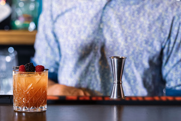 Bartender making delicious cocktails in the bar. (high ISO and shallow dept of focus image)