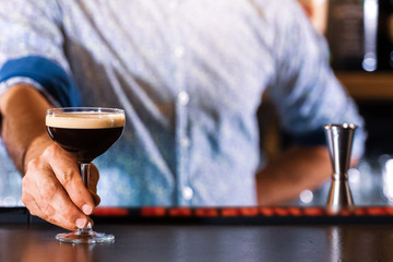 Bartender making delicious cocktails in the bar. (high ISO and shallow dept of focus image)