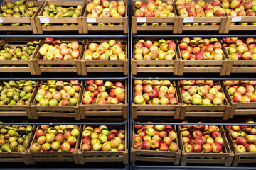 Supermarket counter with a lot of wooden boxes with fresh apples and pears