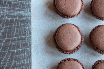 close up of chocolate macarons on wooden background