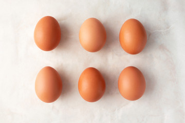Brown organic eggs on marble background, top view. Easter minimalism concept