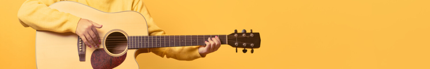 Fototapeta premium guitar in hands over yellow background, panoramic mock up image