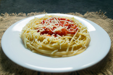  Plate with delicious Italian pasta spaghetti sauce and grated parmesan cheese on a black background.