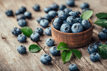 Freshly picked blueberries in wooden bowl on wooden background. Healthy eating and nutrition.