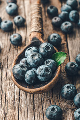 Blueberries in wooden spoon on old wood background. Healthy eating and nutrition concept.