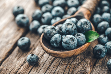 Blueberries in wooden spoon on old wood background. Healthy eating and nutrition concept.