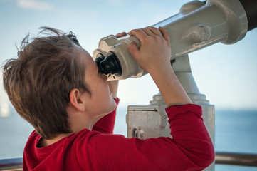 the boy watches the tourist telescope on