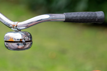 Am Fahrradlenker hängende verchromte und poliert glänzende Fahrradklingel ist dekorativ am verchromten Fahrradlenker und sorgt für Verkehrssicherheit