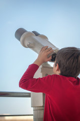 the boy watches the tourist telescope on