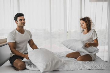a man and a woman playing pillow on the bed