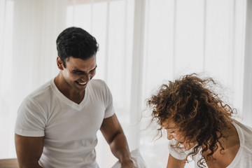a man and a woman playing pillow on the bed