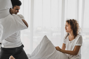 a man and a woman playing pillow on the bed