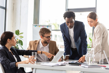 multiethnic businesspeople in formal wear at table during conference in office