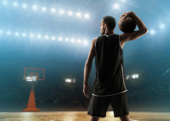 Young professional basketball player with a ball on a floodlit sports arena