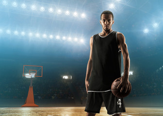 Young professional basketball player with a ball on a floodlit sports arena