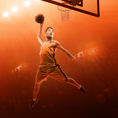 Basketball player in action on a red floodlit sports arena. Slam dunk.