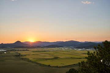 A sunset view of the mountains and fields near the Suncheonman Bay Wetland Reserve in South Korea.
