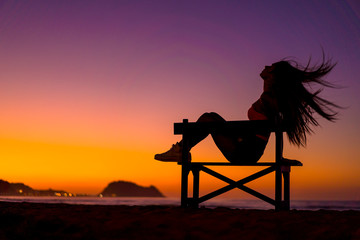 Zarautz, Gipuzkoa / Spain »; September 2019: Lifestyle, a girl sitting on a chair in summer sunset moving her hair from top to bottom